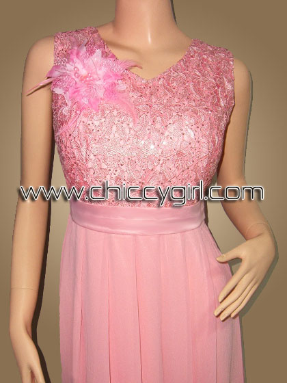 ชุดราตรียาวสีชมพู คอวี แขนกุด ผ้าลูกไม้ถักไหมเงามันลายดอกไม้ ประดับเลื่อม ตกแต่งเข็มกลัดดอกไม้ที่อก กระโปรงผ้าชีฟองพริ้ว แบบสวย สุภาพ เรียบร้อย น่ารัก หรูหราสง่างามมาก